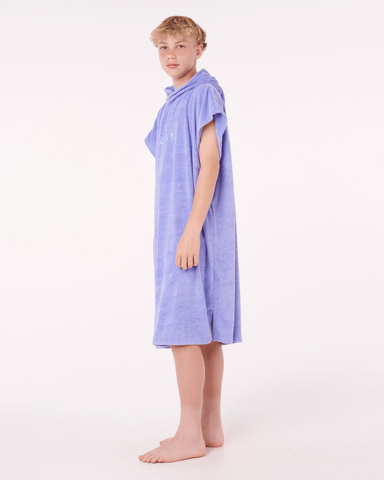 Side view of boy wearing purple Rip Curl hooded towel with short sleeves.