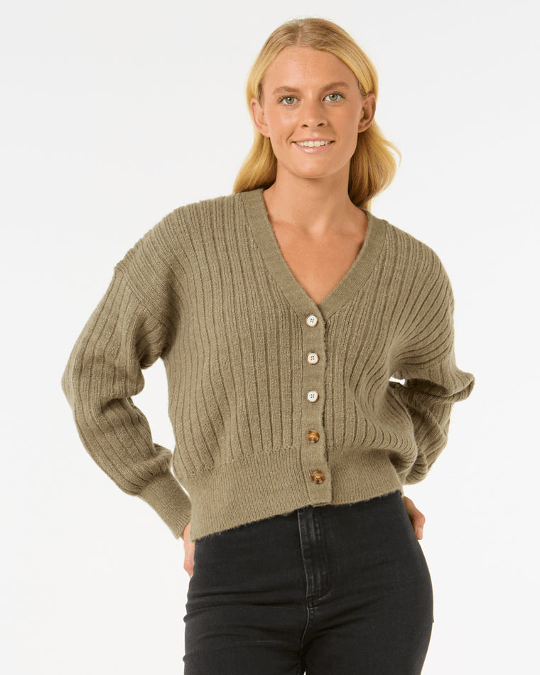 Model wearing an olive green ribbed knit cardigan with a V-neckline, button-down front, and long sleeves, paired with black jeans.