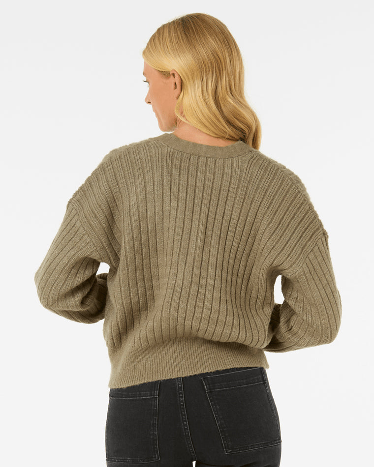 Back view of a model wearing an olive green ribbed knit cardigan with a relaxed fit, paired with black jeans.