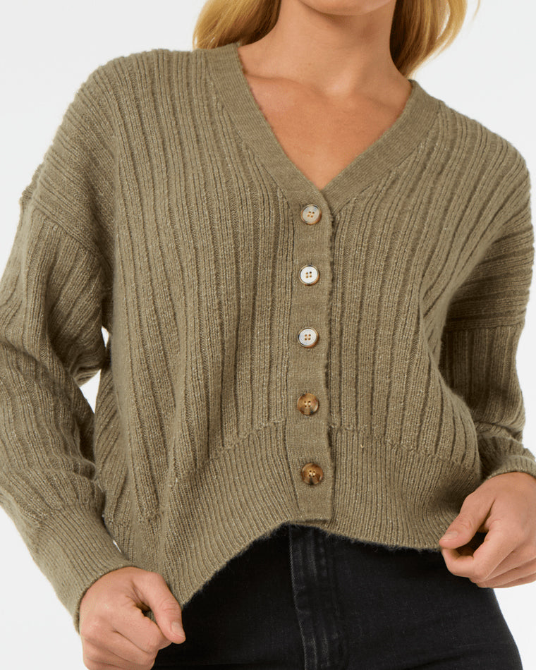 Close-up of an olive green ribbed knit cardigan with a V-neckline and mixed buttons, worn with black jeans