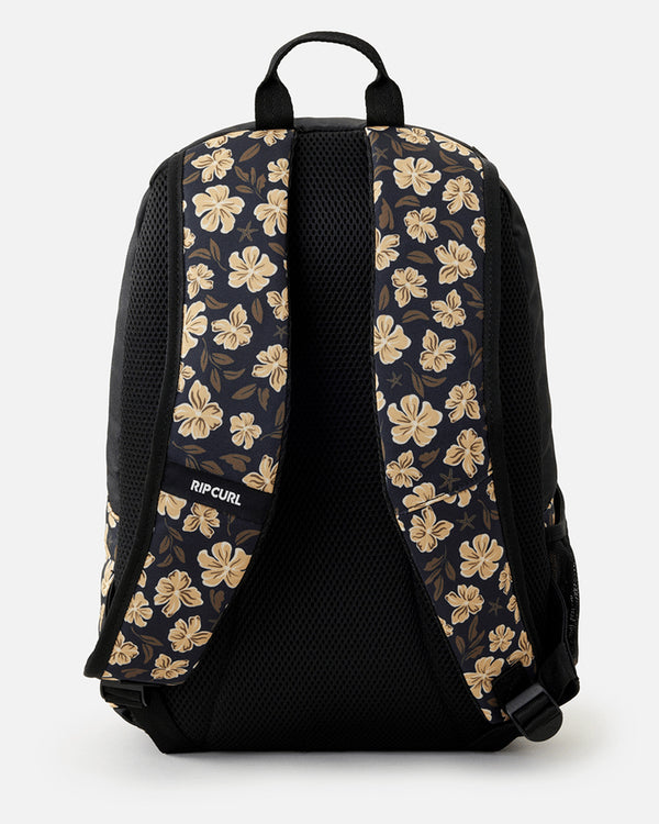 Back view of a black Rip Curl backpack featuring beige floral-patterned padded shoulder straps, mesh backing, and a carry handle.