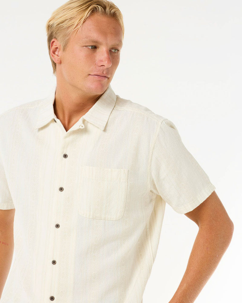 Close-up of cream shirt showing dark buttons and neat chest pocket detailing.