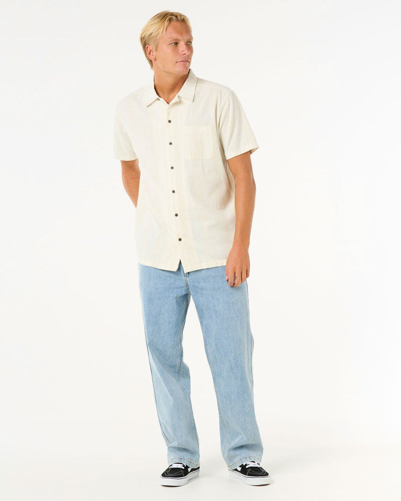 Full outfit featuring a cream button-up shirt, straight-leg light denim and black skate sneakers.