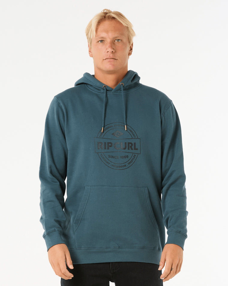 Model wearing a teal Rip Curl hoodie featuring a drawstring hood, kangaroo pocket, and a vintage-style logo print on the chest.