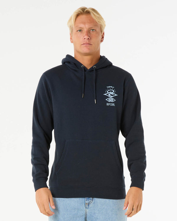 Man wearing a navy Rip Curl hoodie with a small front logo, drawstring hood, and kangaroo pocket, paired with jeans.