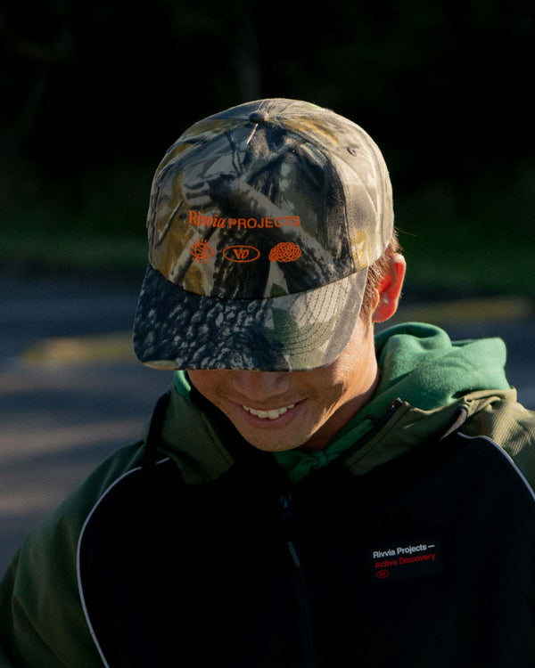 Camo cap with Rivvia Projects logo and orange embroidery