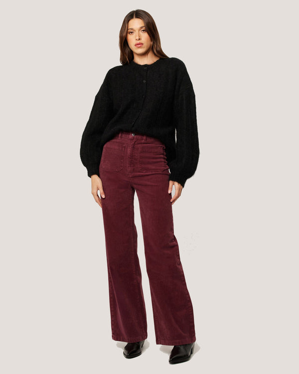 Wide leg burgundy cord pants styled with a black knit and heeled boots for a cosy look