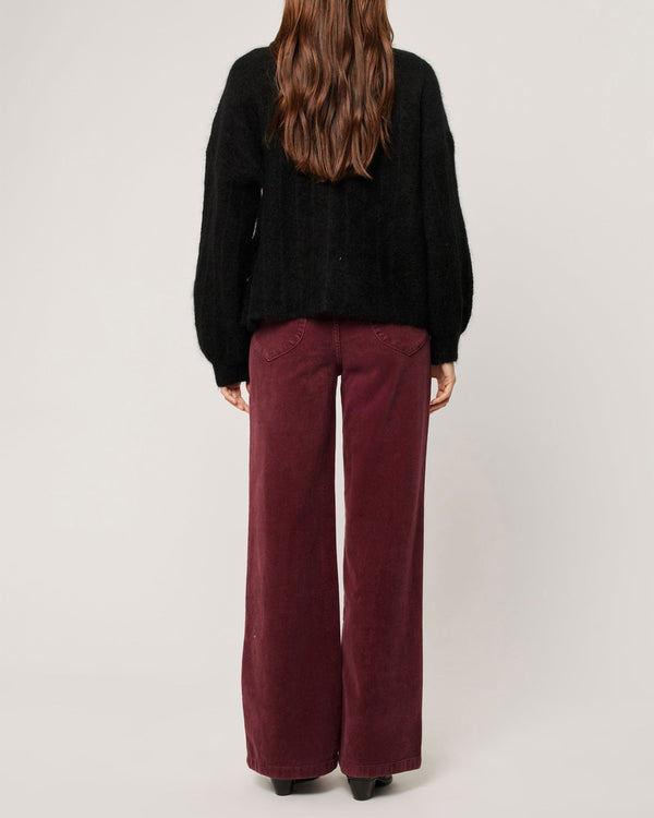 Back view of burgundy cord pants with patch pockets styled with a black knit jumper
