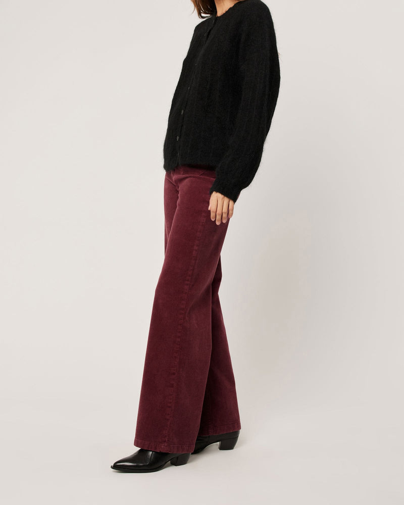 Side view of wide leg burgundy cord pants paired with black heeled boots