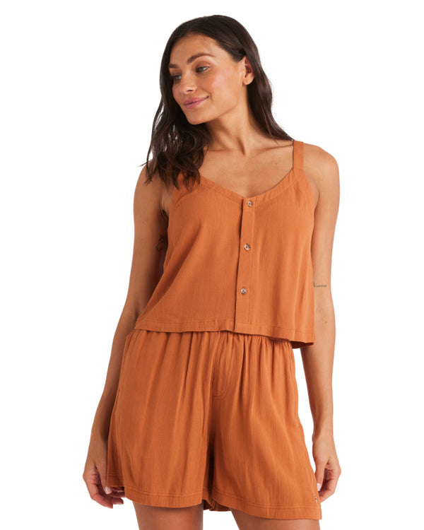 Woman wearing a rust orange button-front tank top and matching relaxed shorts, facing forward.