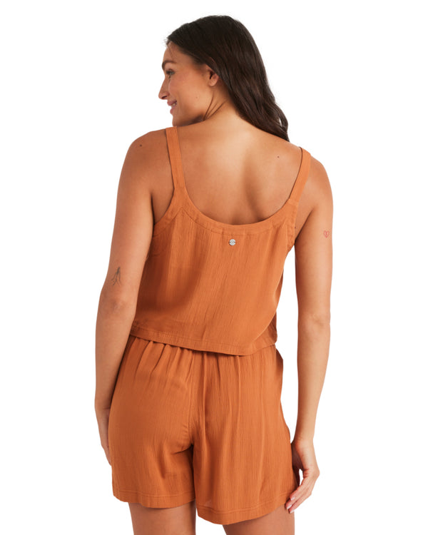 Back view of a woman in a rust orange two-piece set with thick straps and an elastic waistband.