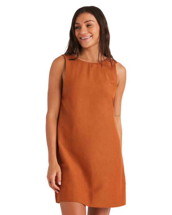 Woman wearing a sleeveless rust mini dress with a high neckline and relaxed fit.