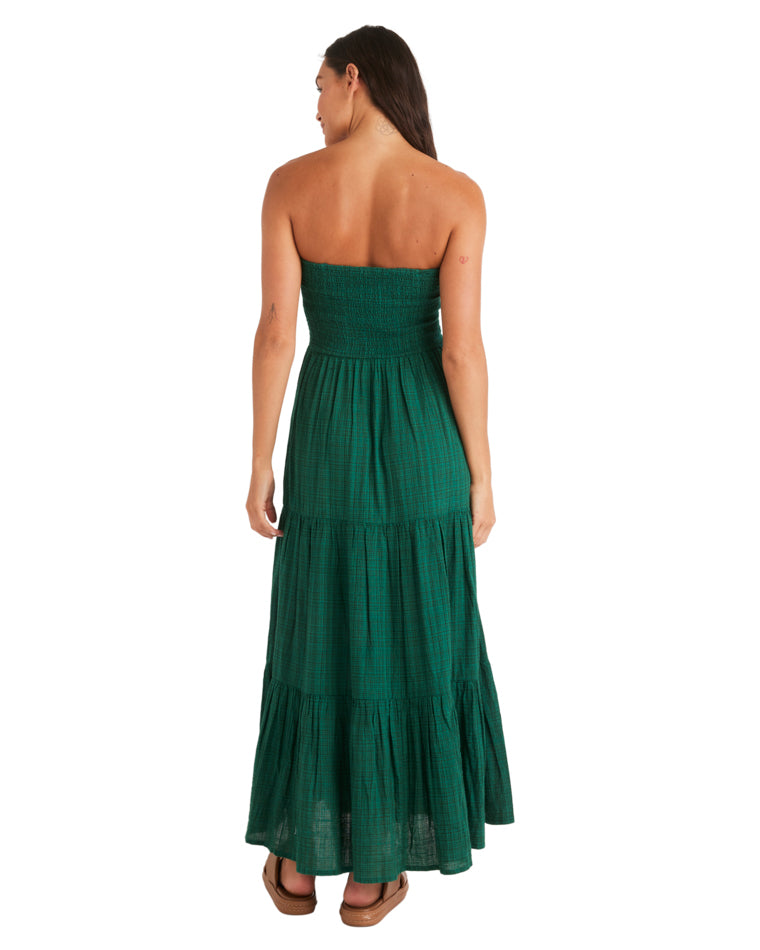 Back view of a woman in a strapless green tiered maxi dress with a fitted bodice and relaxed skirt.