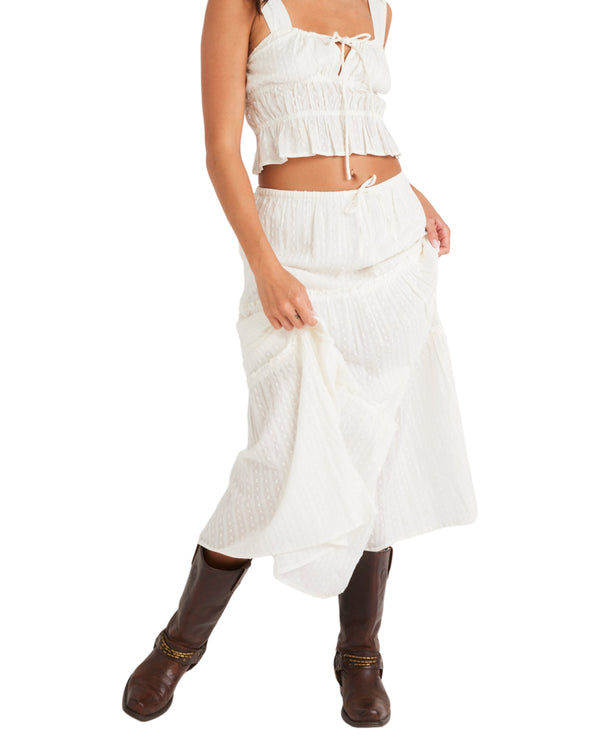 Front view of a white tiered maxi skirt with an elastic waistband and subtle textured dot pattern.