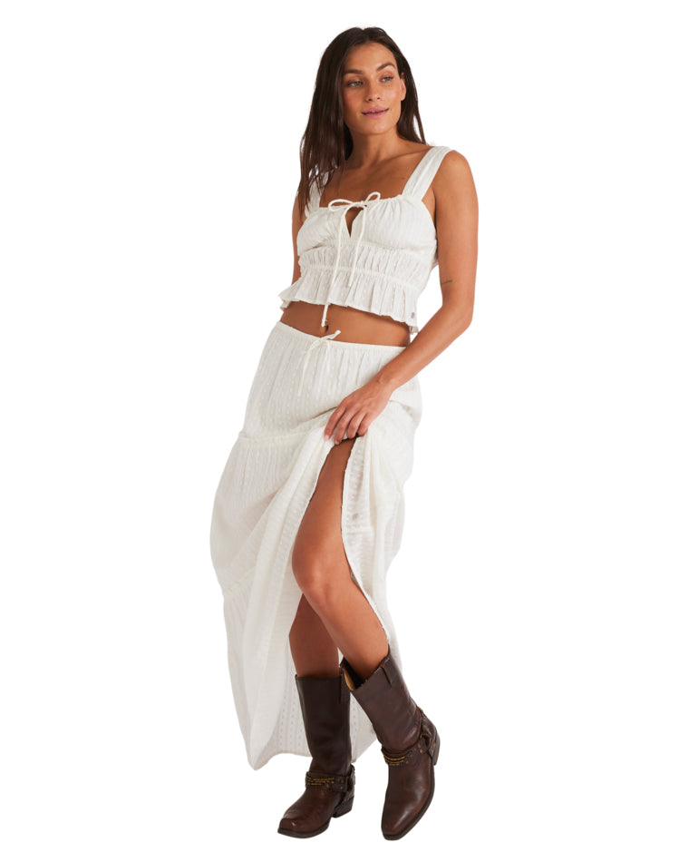 White textured maxi skirt with a front slit, styled with brown boots.