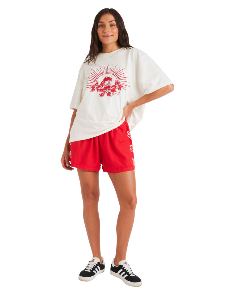 Full-body view of model wearing graphic white tee and red shorts with floral embroidery.