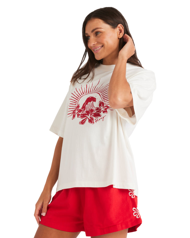 Side view of white graphic tee featuring red surf design, worn with red shorts.