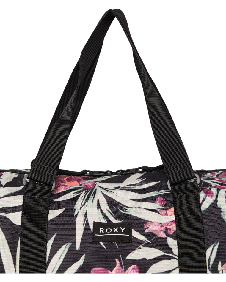 Close-up of Roxy logo patch and handles on floral print duffle bag.