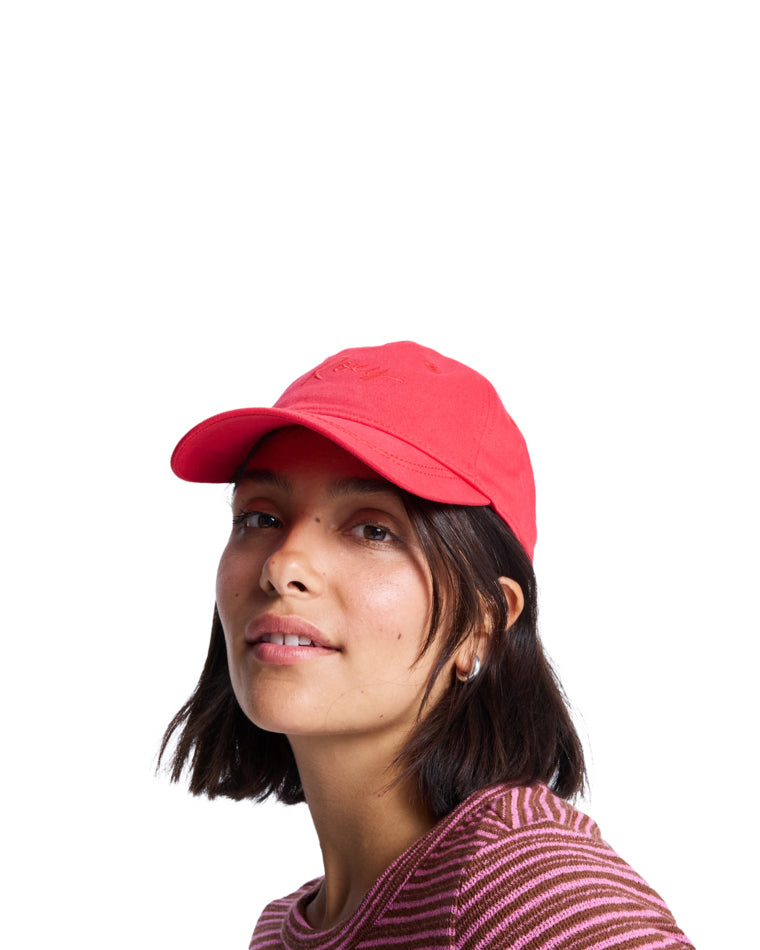 Woman wearing a red Roxy cap with curved brim and tonal logo embroidery.