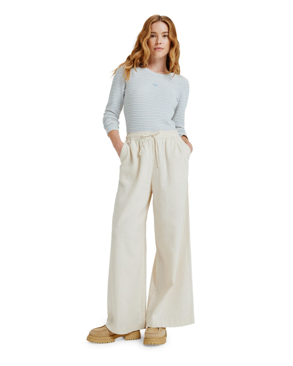 Woman wearing cream wide-leg pants with drawstring waist and side pockets.