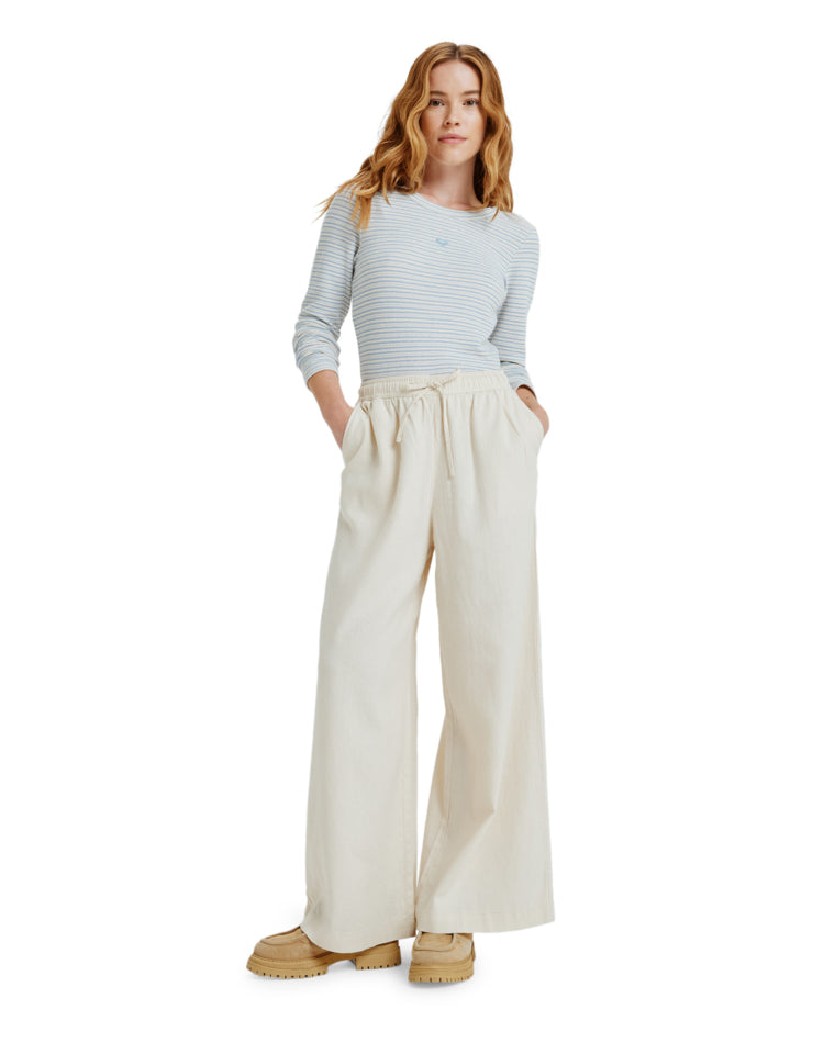 Woman wearing cream wide-leg pants with drawstring waist and side pockets.