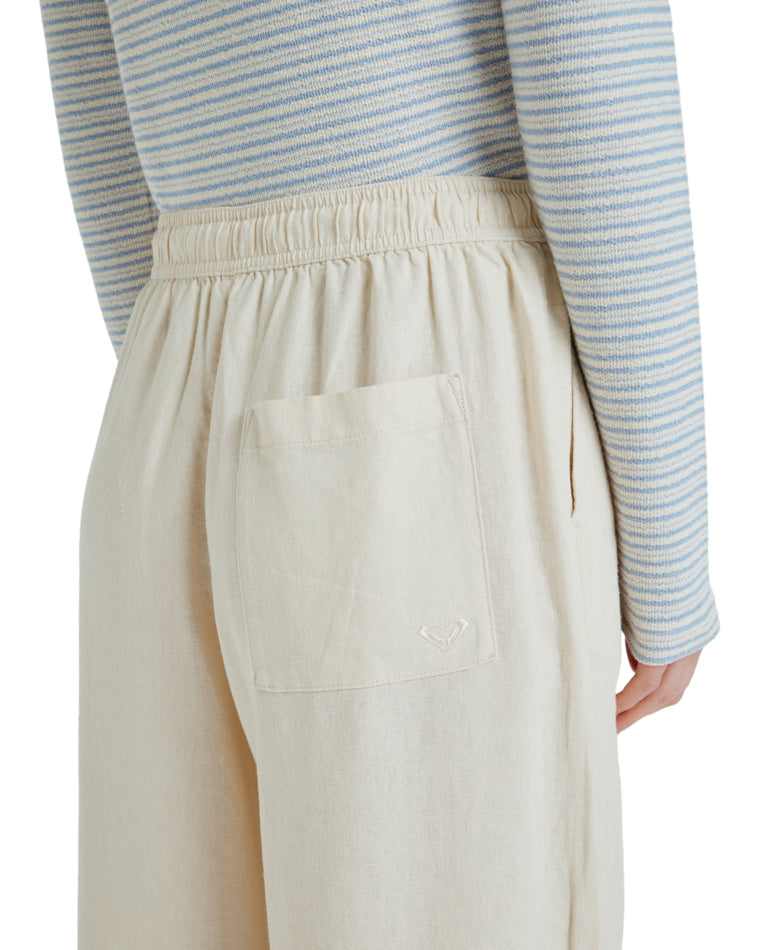 Close-up of back pocket on cream wide-leg pants with subtle embroidered logo.
