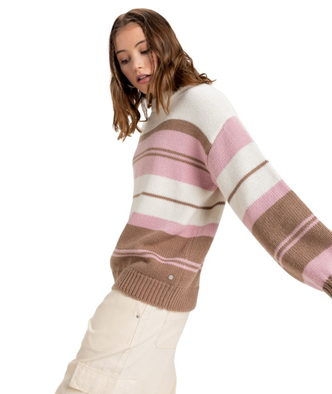 Side view of a woman wearing a striped knit sweater in brown, pink, and white, paired with beige cargo pants.
