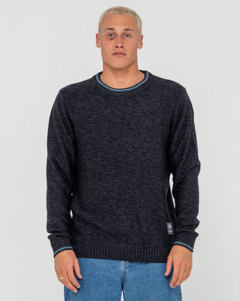 Male model wearing a dark navy knit sweater with ribbed cuffs and hem, featuring subtle blue trim on the collar and sleeves.