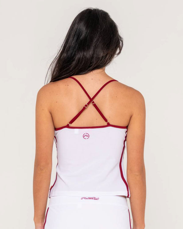 Back view of a female model wearing a white tank top with red contrast piping and adjustable crisscross straps.