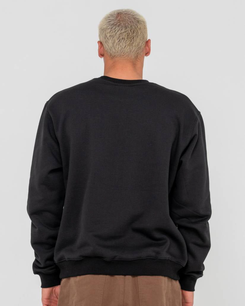 Back view of a man wearing a black crewneck sweatshirt with a relaxed fit, paired with brown pants.