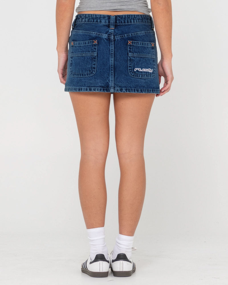 Back view of a denim skirt with back pockets featuring orange stitching and a logo detail.