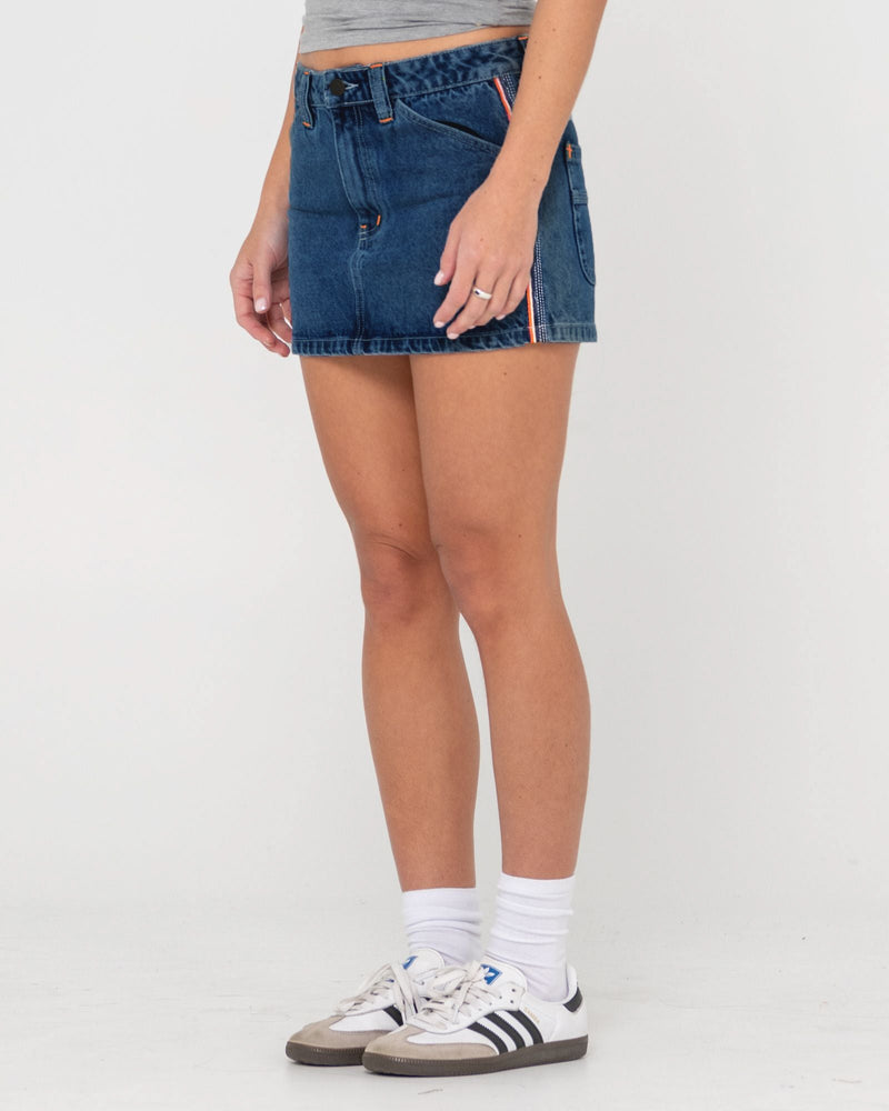 Side view of a denim skirt with a button-up closure and orange accent stripe on the side.