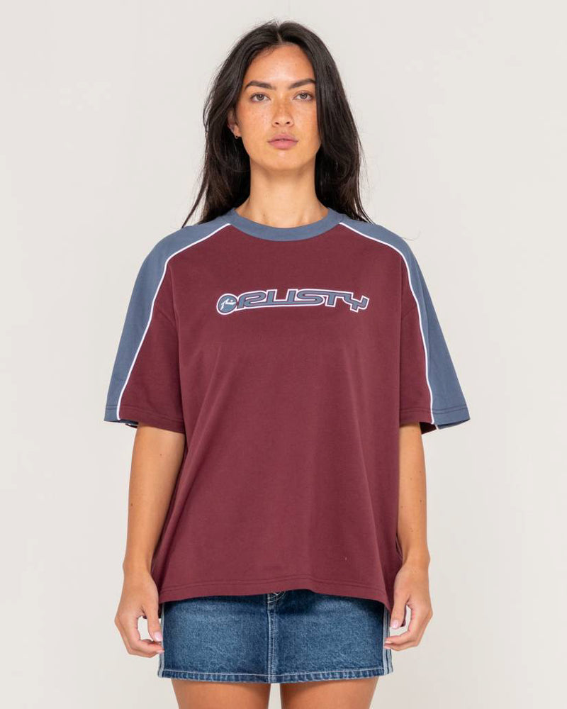 Rusty oversized T-shirt in burgundy with navy contrast sleeves and white piping, featuring a logo print, styled with a denim skirt.