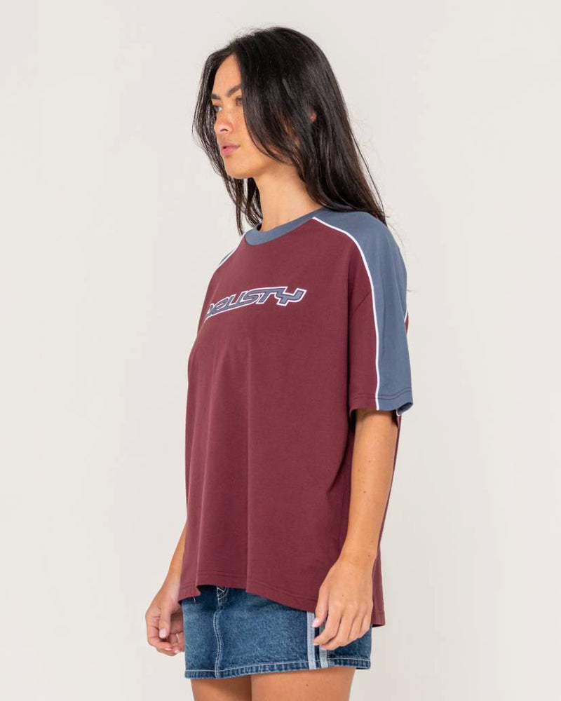 Side view of a Rusty oversized T-shirt in burgundy with navy contrast sleeves and white piping, paired with a denim skirt.