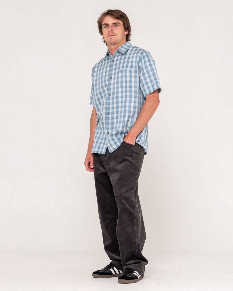 Full outfit view with blue check shirt, black cord pants and black sneakers
