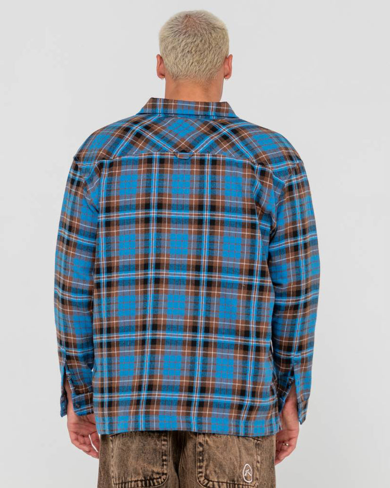 Back view of a man wearing a blue and brown plaid button-up flannel shirt with a relaxed fit and long sleeves.