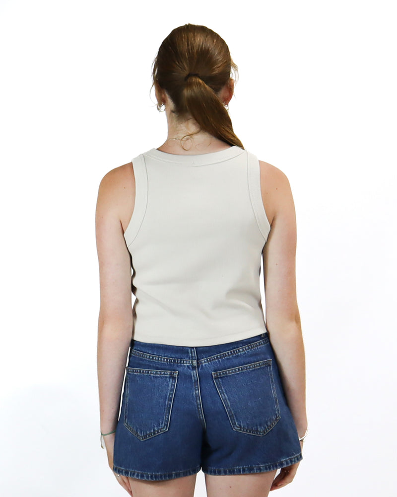 Back view of a beige cropped tank top with a classic racerback design, paired with high-waisted dark denim shorts.