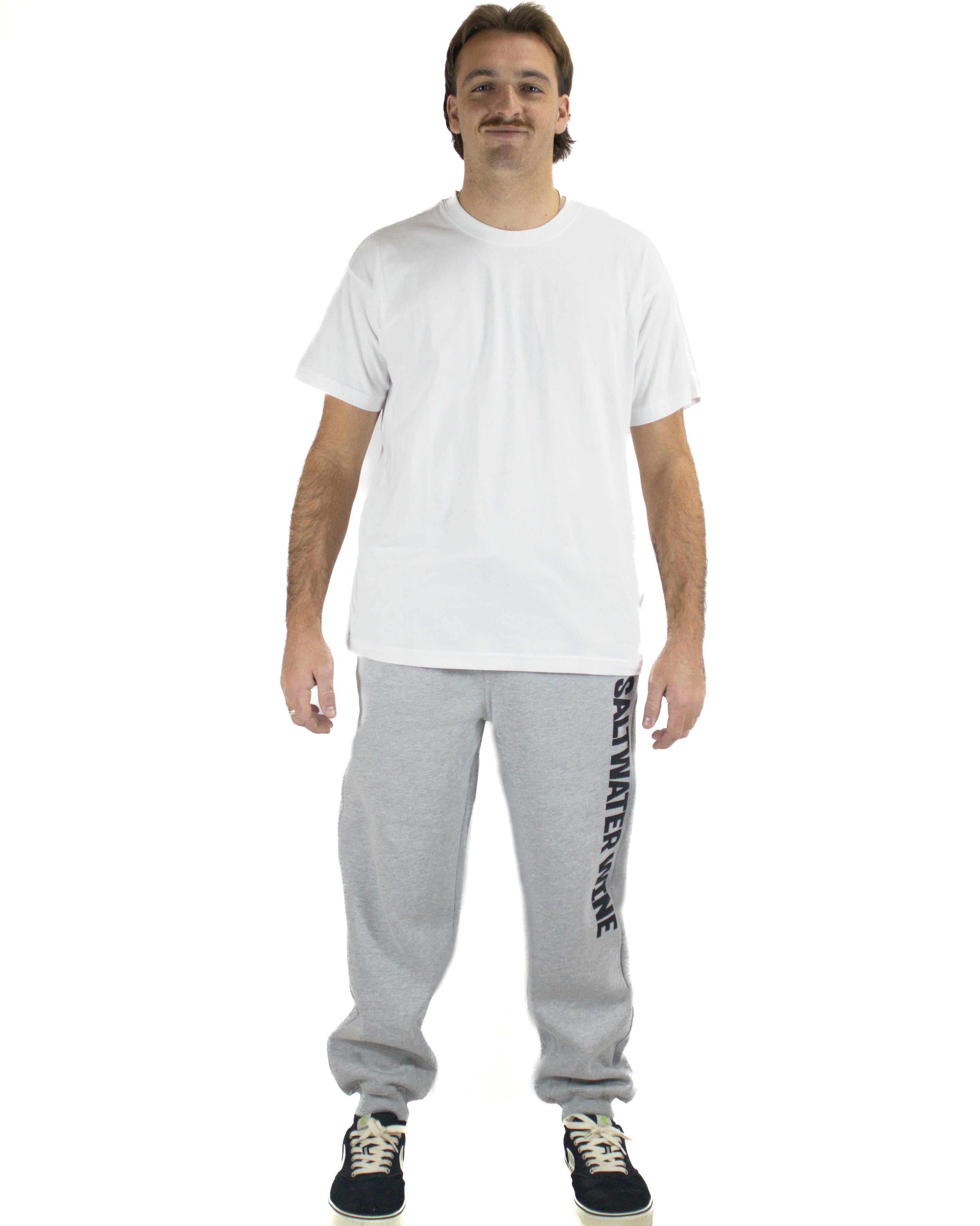 Man wearing grey Saltwater Wine trackpants with black sneakers and white tee
