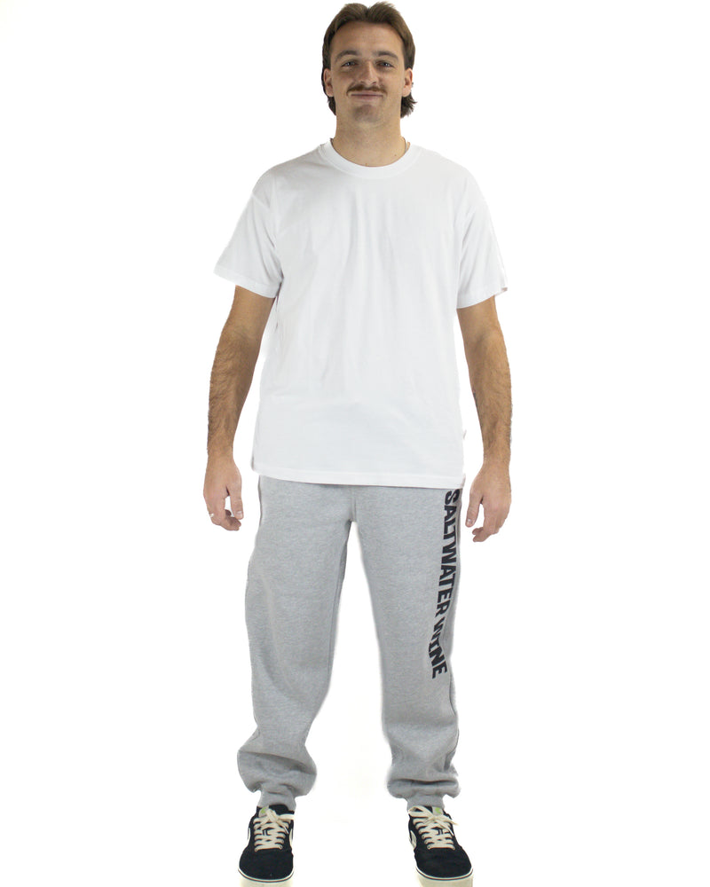 Man wearing grey Saltwater Wine trackpants with black sneakers and white tee