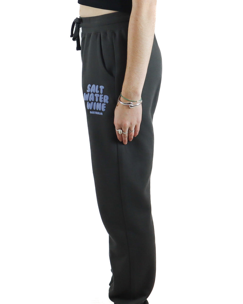 Side profile of charcoal trackpants with lilac Salt Water Wine logo on the thigh