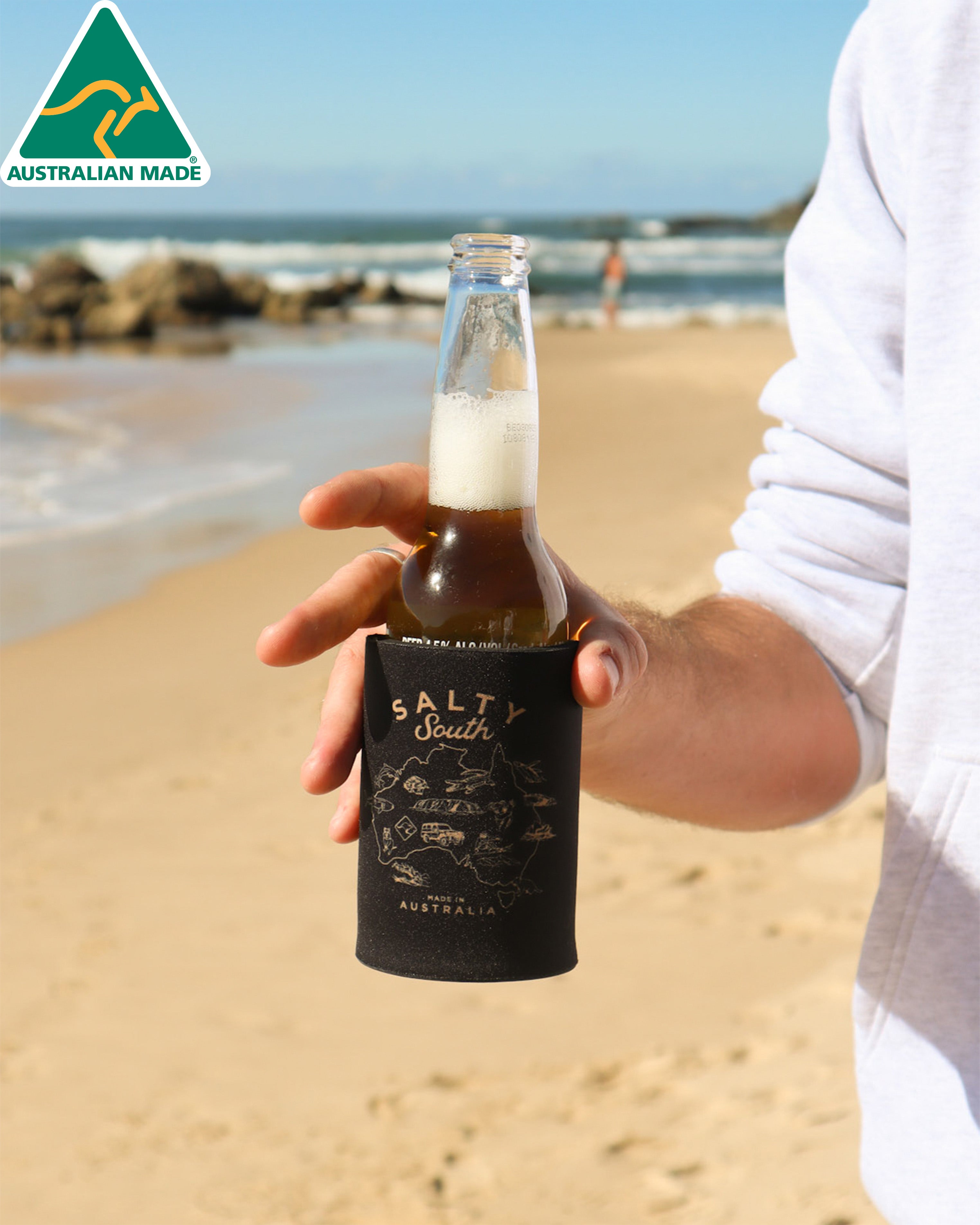 Black Salty South stubby holder with gold illustrated Australia map, made in Australia and shown holding a beer