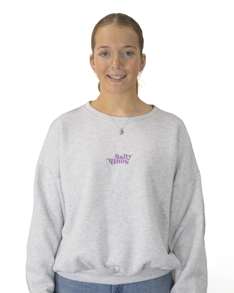 Studio shot of grey Salty South jumper with purple front logo, relaxed fit and soft fleece for everyday wear.
