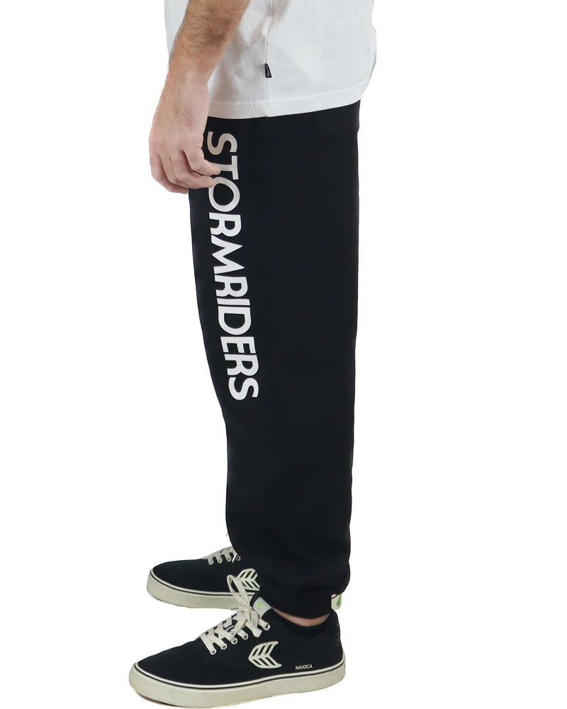 Side view of black trackpants with bold white Stormriders logo down the left leg