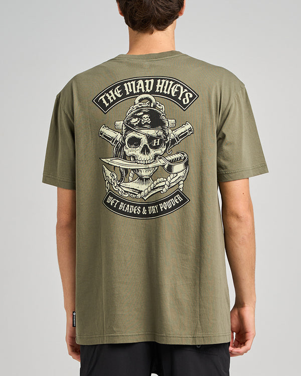 A model wearing an olive green t-shirt featuring a large skull graphic on the back with the text "The Mad Hueys.