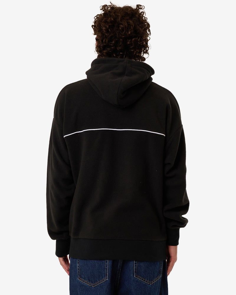 Back view of a black oversized hoodie with a white horizontal stripe, large hood, and ribbed cuffs, worn with denim jeans.