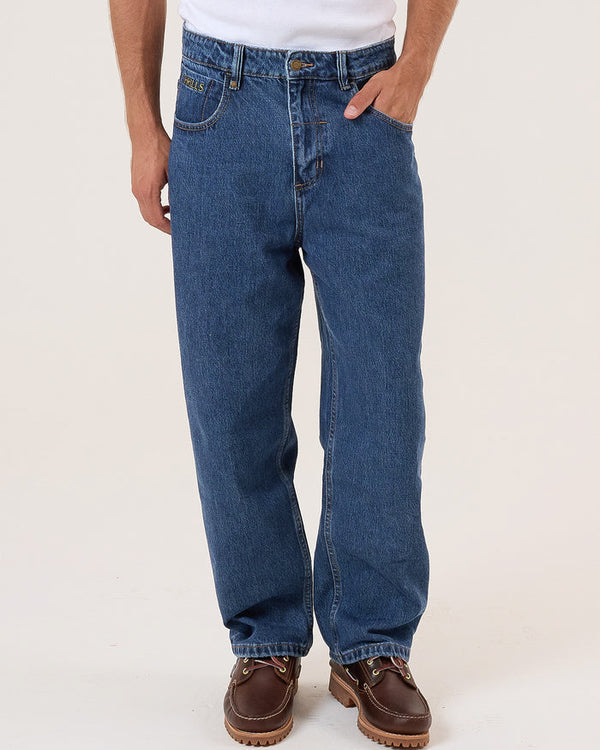 Men's straight-leg blue denim jeans with contrast stitching, front pockets, and brown leather shoes, worn with a white tee.