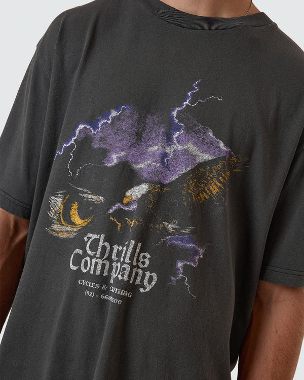 Close up of Thrills Company eagle and lightning graphic on faded black tee