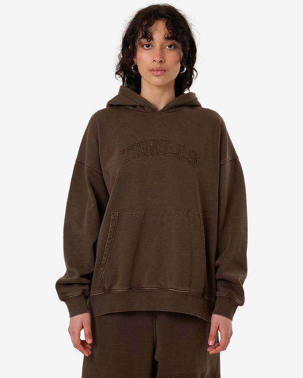 Female model wearing an oversized brown Thrills hoodie with embroidered logo, kangaroo pocket, and matching brown pants.