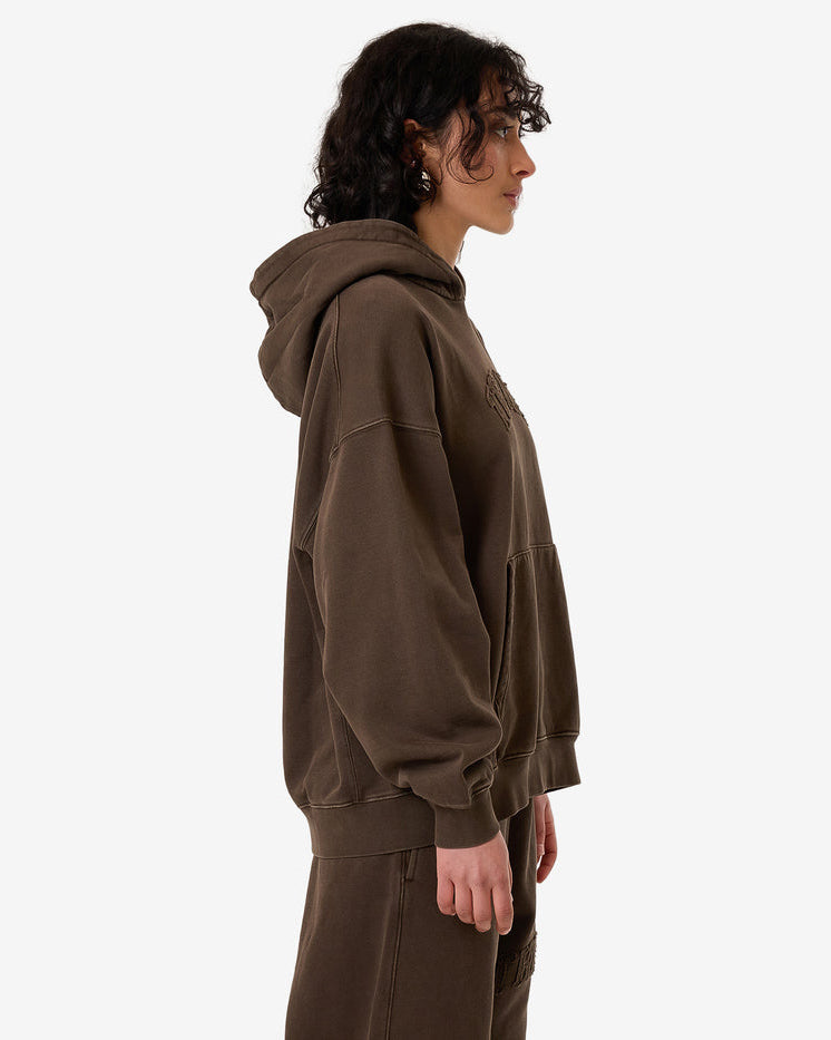 Side view of a female model wearing an oversized brown Thrills hoodie with a relaxed fit, large hood, and matching pants.