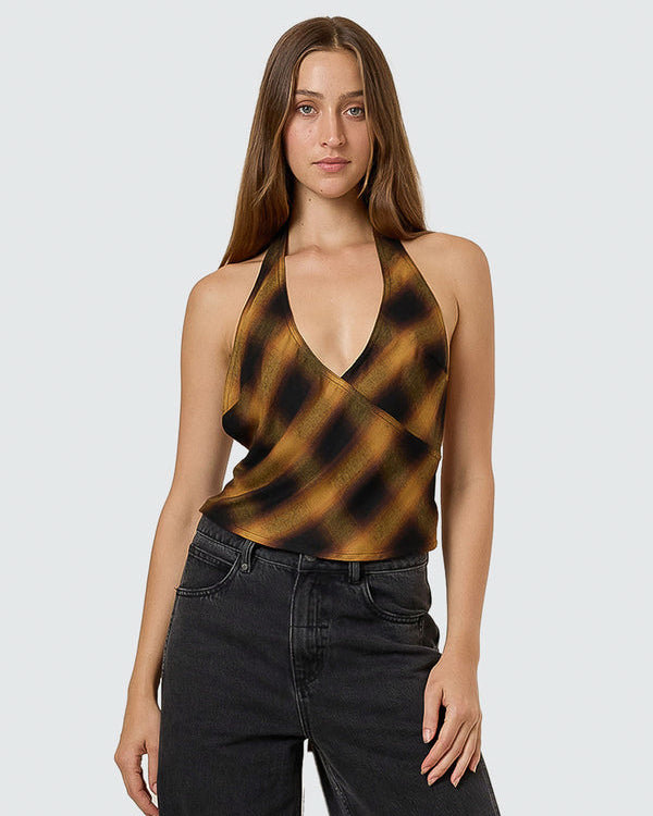 Front view of a model wearing a brown and black checkered halter top with a deep V-neck and black jeans.